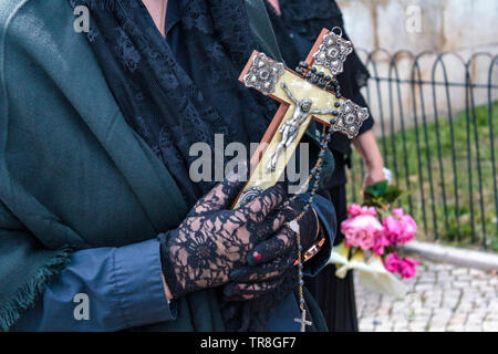 Widow hands holding a religious cross and a rosary Stock Photo