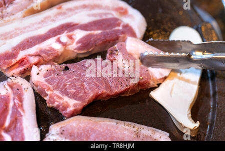 Pan-fried black pork meal in Korea restaurant, fresh delicious korean food cuisine on iron plate with lettuce, close up, copy space, lifestyle Stock Photo