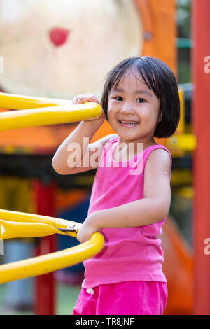 Asian Chinese little girl climbing at outdoor playground alone Stock Photo