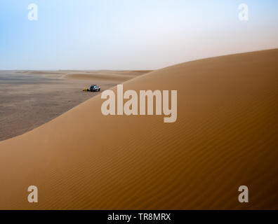 Desert atmosphere in the morning in the desert Sahara in Sudan on a big sand dune with the tent and the jeep in the background Stock Photo