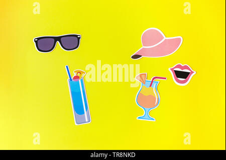 Two abstract faces made of photo booth props on yellow background. Pop art style image of a man and a woman on summer holiday. Summer concept. Top vie Stock Photo