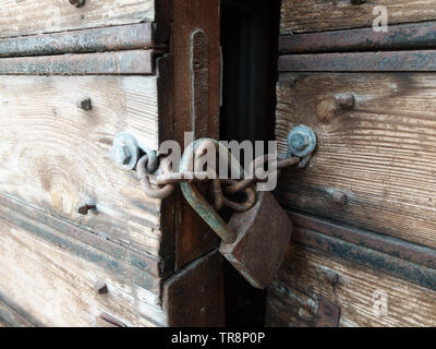 Wooden weathered antique gates closed with padlock. Stock Photo