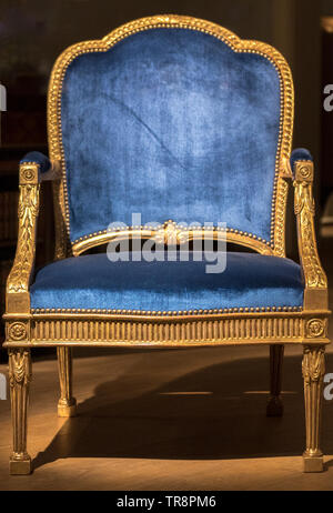 Large Blue Fabric Throne Chair with Gold Frame in Spotlight Stock Photo