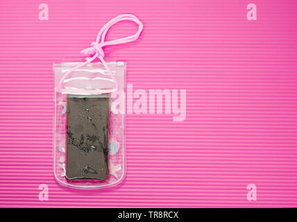 Waterproof Mobile Phone Case with Water Droplets Isolated on Pink Mat Background. Plastic PVC Waterproof Case for Smartphone, Zip Lock Bag Protect. Stock Photo