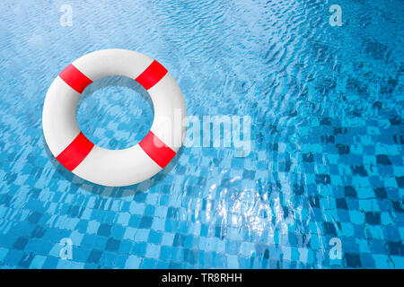 Life Buoy in a Clear Pool Water. Liferreserver Floating on Top of Sunny Blue Water. Safety Equipment, Blue and White Lifebelt in Swimming Pool. Stock Photo