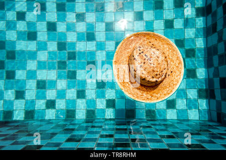 Vintage Wicker Hat Fashion for People in Aqua Swimming Pool and Flow with Waves Background. Top View of Straw Hat with Summer Holiday. Brown Cap. Stock Photo