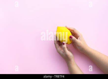 Young female hand holding lemon on pink pastel background.fruit and healthy concepts ideas Stock Photo