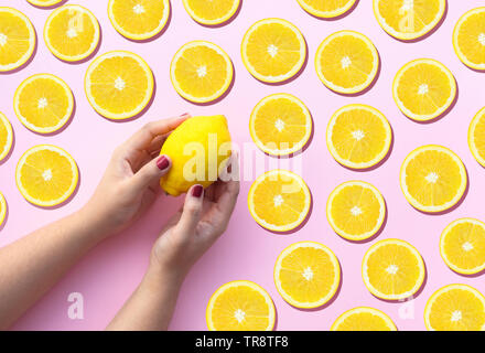 Young female hand holding lemon with a lot of  lemon slice on pink pastel background.fruit and healthy concepts ideas Stock Photo