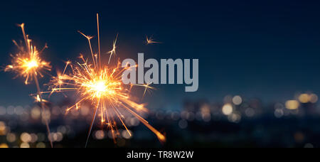 Burning sparkler with blurred bokeh cities light background Stock Photo