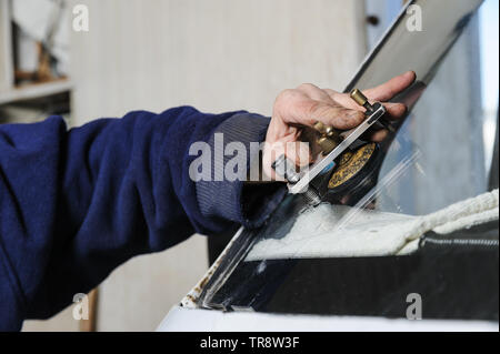 Repair cracked windshield. The fitter is using Windshield Repair Crack Bridge. Stock Photo