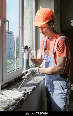 Worker is using a polyurethane foam for installation of window sill. Stock Photo