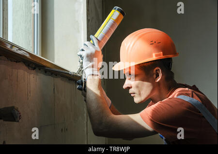 Worker is using a polyurethane foam for installation of window sill. Stock Photo