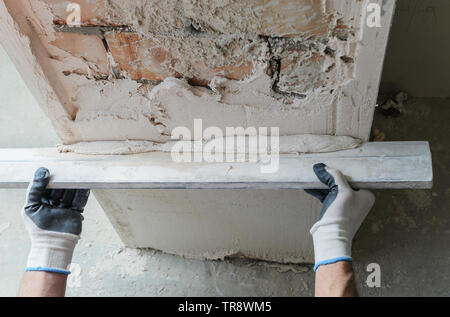 Worker is putting a gypsum plaster on a brick wall. Stock Photo