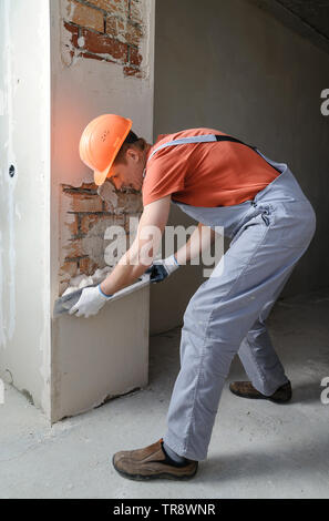 Worker is putting a gypsum plaster on a brick wall. Stock Photo