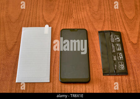 Preparation of the material to install a protective glass cover on the smartphone screen. The sachet with the screen cleaning kit was opened on the wo Stock Photo
