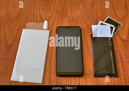 Preparation of the material to install a protective glass cover on the smartphone screen. The sachet with the screen cleaning kit was opened on the wo Stock Photo