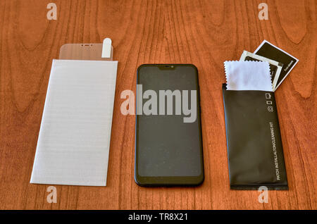 Preparation of the material to install a protective glass cover on the smartphone screen. The sachet with the screen cleaning kit was opened on the wo Stock Photo