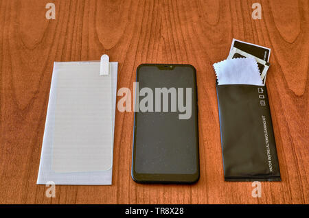 Preparation of the material to install a protective glass cover on the smartphone screen. The sachet with the screen cleaning kit was opened on the wo Stock Photo
