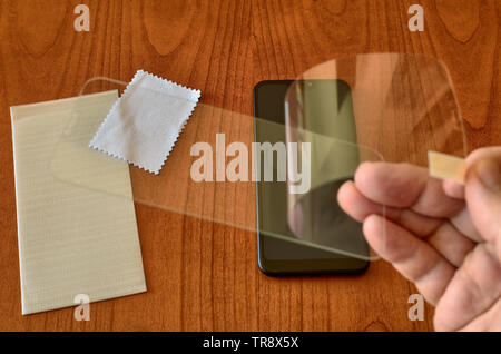 In the foreground the film is removed from the slide in order to proceed with the installation. In the background, on the table, the telephone with th Stock Photo
