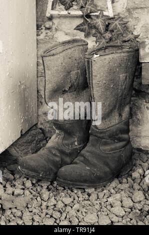 Pair of old vintage used winter high knee boots made of felt and leather. Aged photo Stock Photo