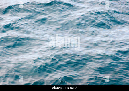Blue sea surface with waves and ripples. Top view sea texture, unfocused. Stock Photo