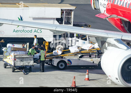Bali, Denpasar, 2018-05-01: Airport workers loading catering supplies into aircraft. Ground staff puts the packaging with food from Aerofood ACS Stock Photo