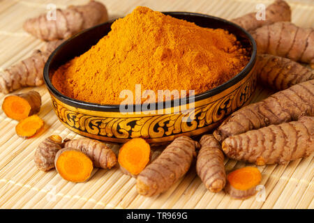 turmeric powder in asian bowl with fresh turmeric roots selective focus on turmeric powder Stock Photo