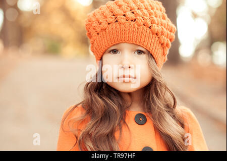 Closeup portrait of cute baby girl wearing knitted hat and winter jacket outdoors. Looking at camera. Childhood. Seasonal. Stock Photo