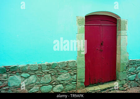 Red wooden door on the concrete and stone wall in aqua blue color Stock Photo