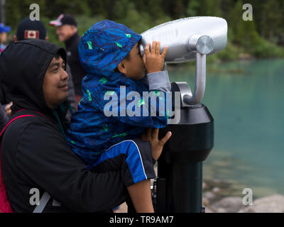 Boy looking through coin-operated binoculars, Lake Louise, Improvement District 9, Banff National Park, Jasper, Alberta, Canada Stock Photo