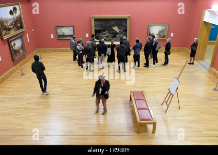 National Gallery London visitors looking at British artist J.M.W. Turner 1805 painting The Shipwreck with tour guide in Central London UK KATHY DEWITT Stock Photo