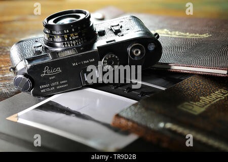 Heavy used Leica M4 camera with photo album on wooden table. The Leica M4 is a 35 mm rangefinder camera produced by Ernst Leitz GmbH from 1966 - 1975. Stock Photo