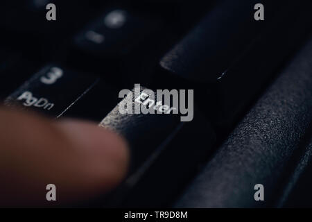 Finger pressing enter key close up Stock Photo