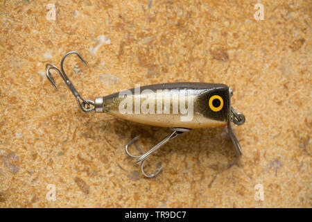 An old wooden fishing lure equipped with three treble hooks for