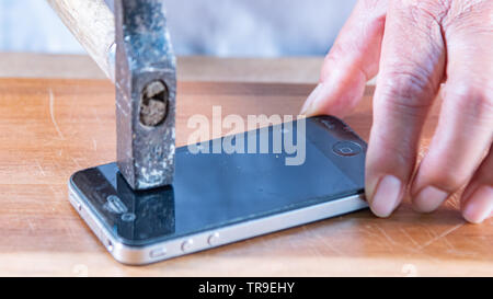smart phone broken with a hammer on a wooden table. blurred picture Stock Photo