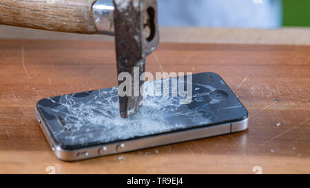 smart phone broken with a hammer on a wooden table. blurred picture Stock Photo