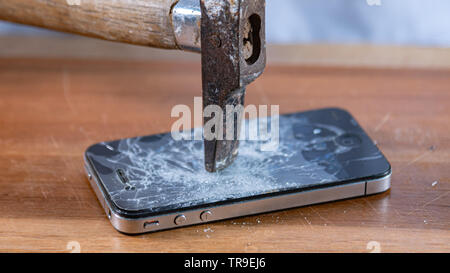 smart phone broken with a hammer on a wooden table. blurred picture Stock Photo