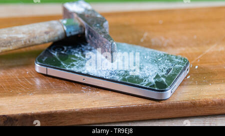 smart phone broken with a hammer on a wooden table. blurred picture Stock Photo