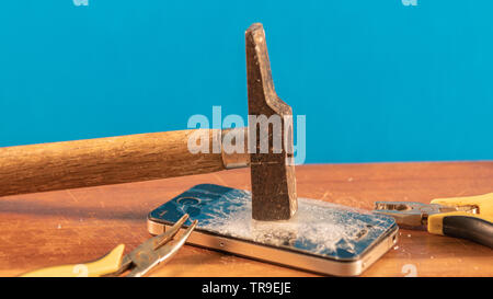 Abstract photo. A Hammer and a smartphone with a broken screen. Cracked iphone Stock Photo