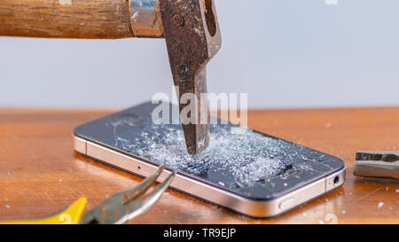An old hammer and smartphone. With broken screen on a white background Stock Photo