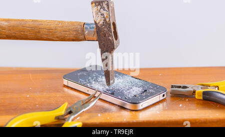 An old hammer and smartphone. With broken screen on a white background Stock Photo