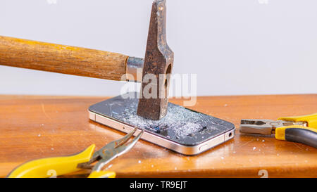 An old hammer and smartphone. With broken screen on a white background Stock Photo