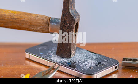 An old hammer and smartphone. With broken screen on a white background Stock Photo