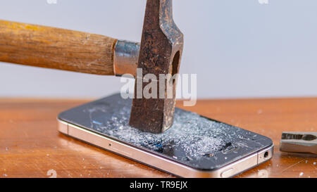 An old hammer and smartphone. With broken screen on a white background Stock Photo