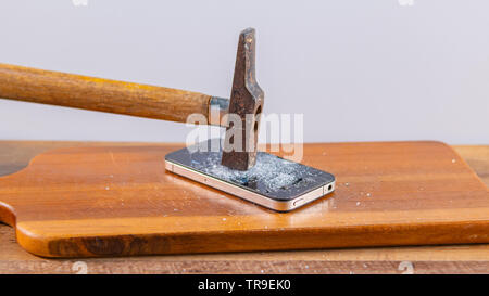 An old hammer and smartphone. With broken screen on a white background Stock Photo
