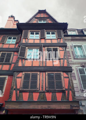 Red colored wooden building facade in Strasbourg city, France, Alsace. Historic town traditional timber framing houses. Medieval fachwerk architecture Stock Photo