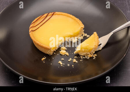 Two lemon tarts on a slate background, with dessert fork Stock Photo