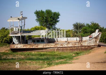 A river Nile cruise boat is left abandoned in a field by the banks of the river in Dongola the capital of the northern state of Sudan Stock Photo