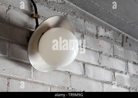 Old electric lamp in the garage brick wall Stock Photo
