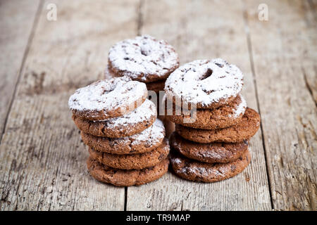 Fresh baked chocolate chip cookies with sugar powder stacks on wooden table background. Stock Photo